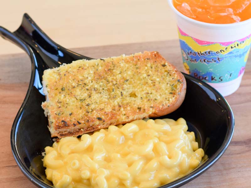 Side sized mac and cheese with a piece of white toast and an kids sized orange pop.