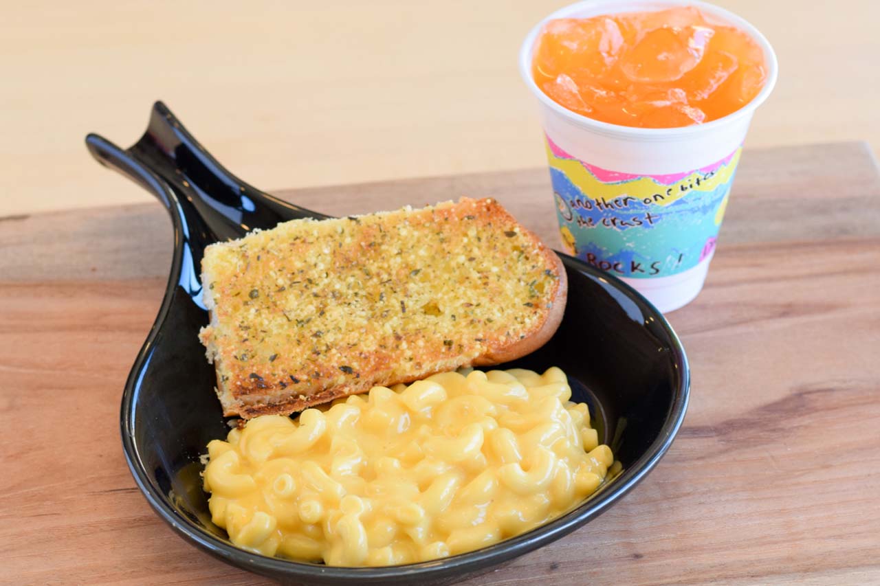 Side sized mac and cheese with a piece of white toast and an kids sized orange pop.