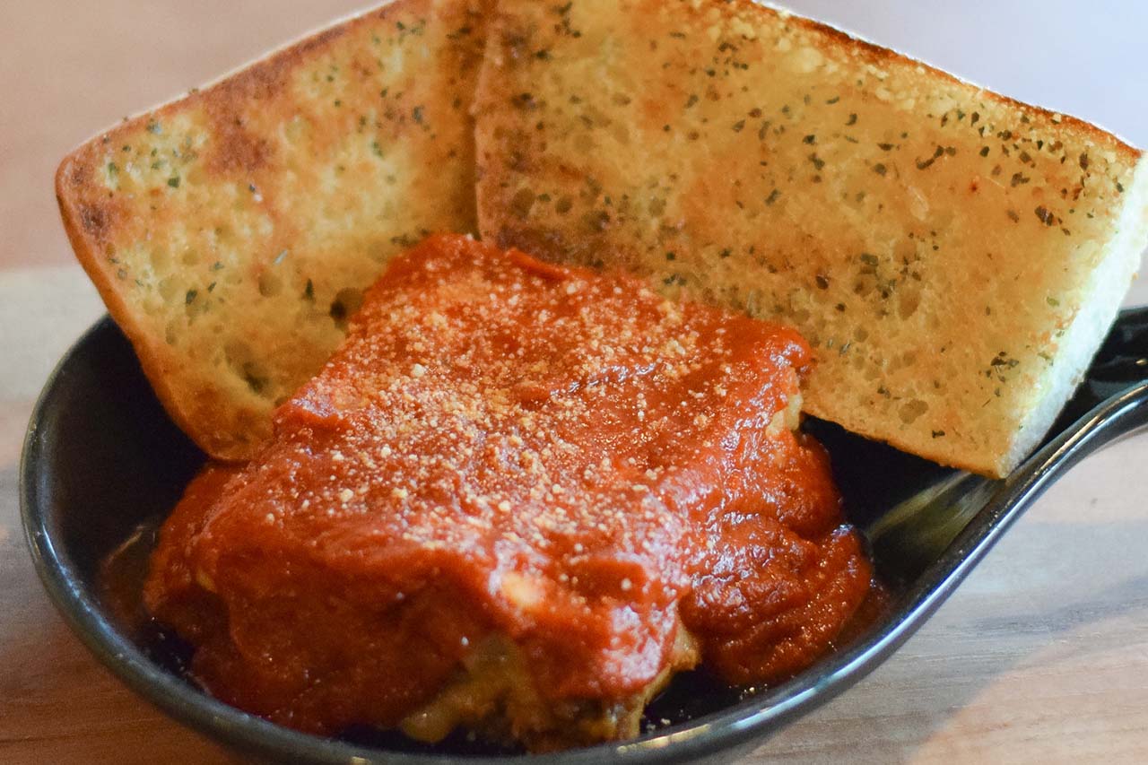 Whole order of lasagna topped with red sauce and a romano cheese sprinkle. Served with Ciabatta Garlic Toast.