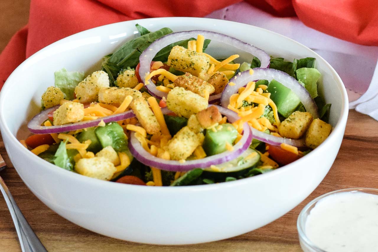 Entree sized garden salad with lettuce, cucumbers, red onions, diced green peppers, tomatoes, croutons, cheese, and a dressing of choice.