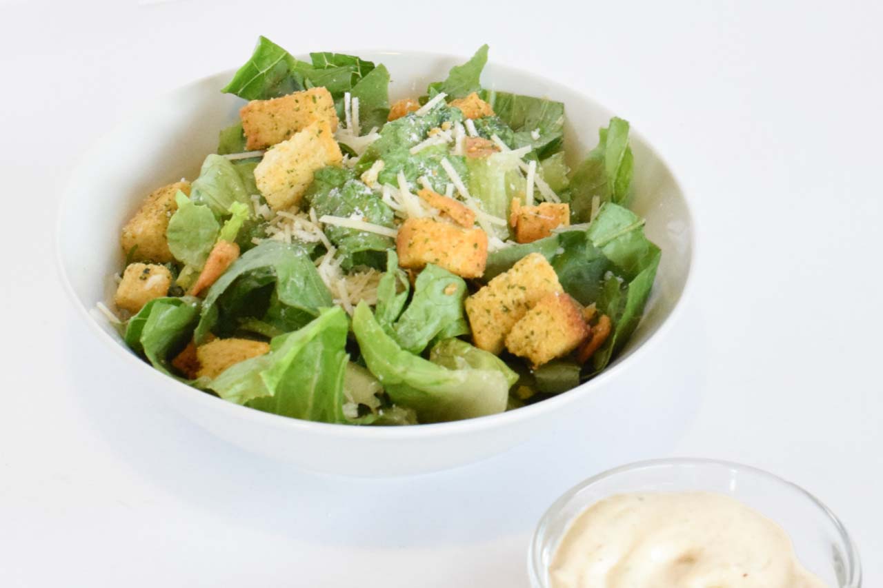 Side sized caesar salad with croutons and sprinkled shredded romano cheese. Served with a side of caesar dressing.