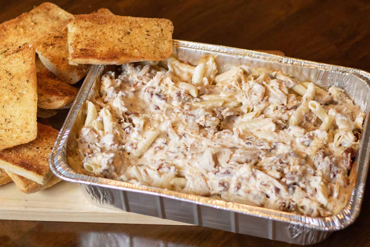 Pan size of Penne Pasta tossed with alfredo sauce, chicken and bacon. Topped with shredded romano cheese and served with ciabatta garlic toast.
