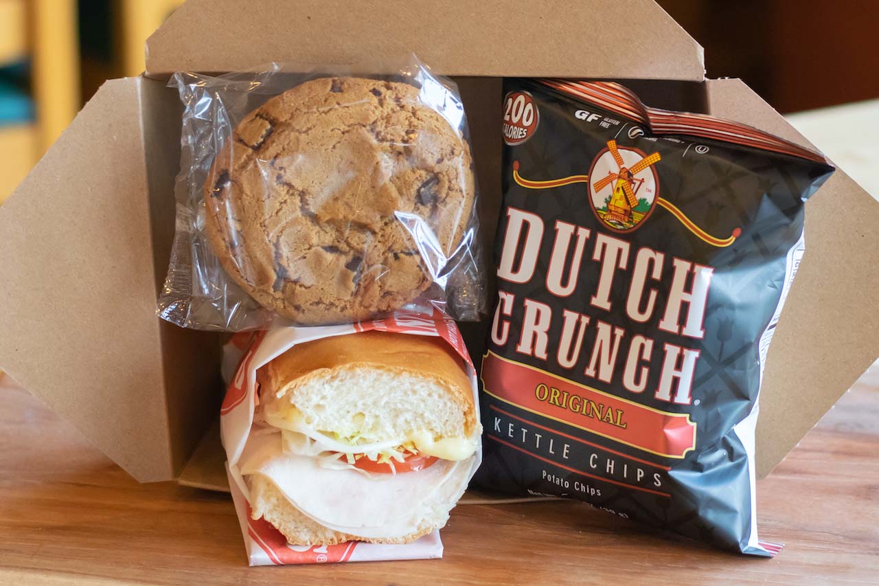 Box lunch with a half cold turkey hoagie, wrapped chocolate chunk cookie, and a bag of original old dutch crunch chips, displayed in a box.