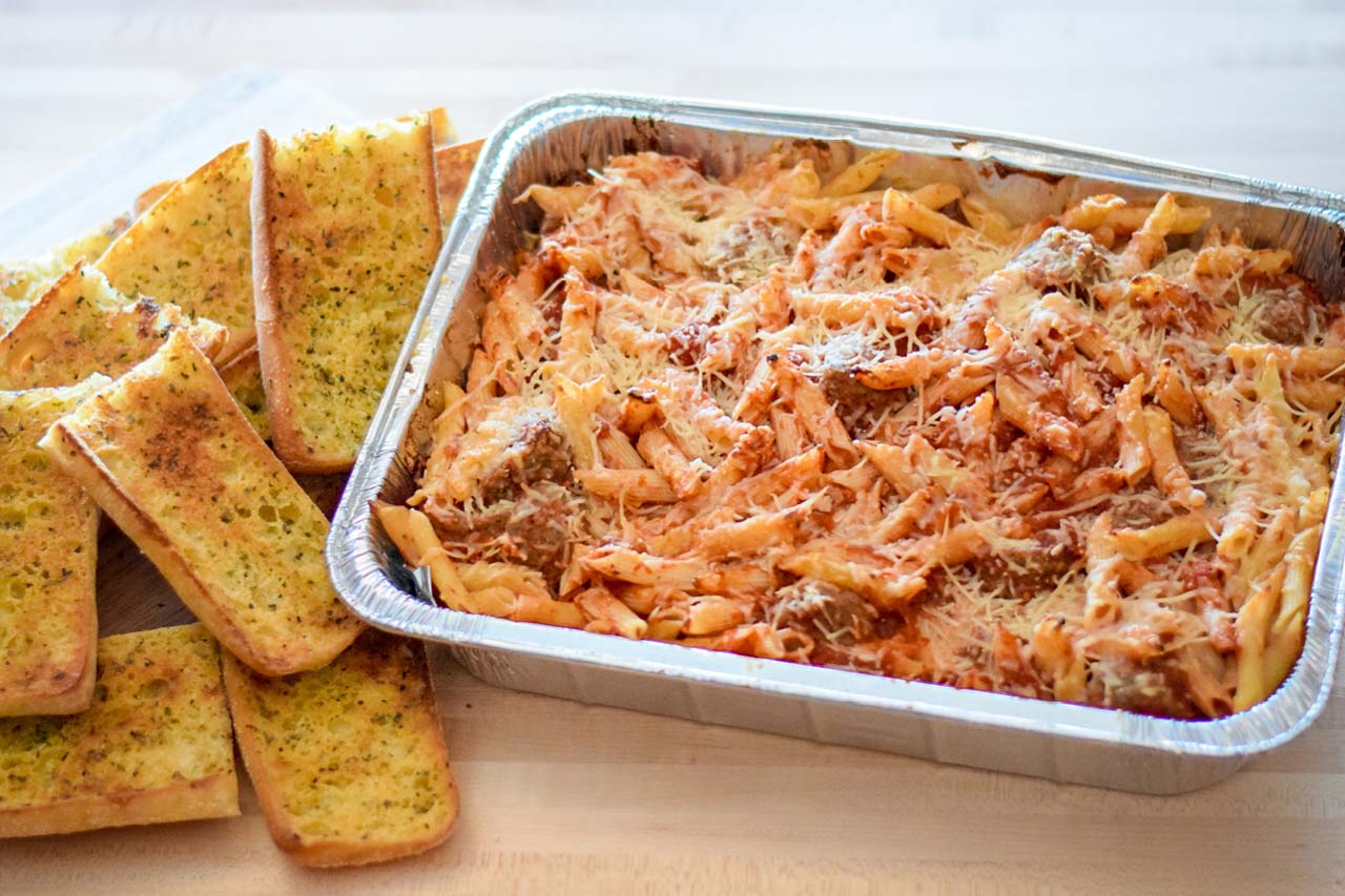 Pan of pasta with red sauce, meatballs, topped with shredded romano cheese. Served with ciabatta garlic toast.