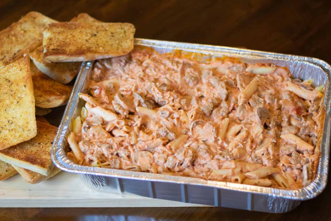 Pan sized penne pasta with red sauce, meatballs, shredded romano cheese, and ciabatta garlic toast.